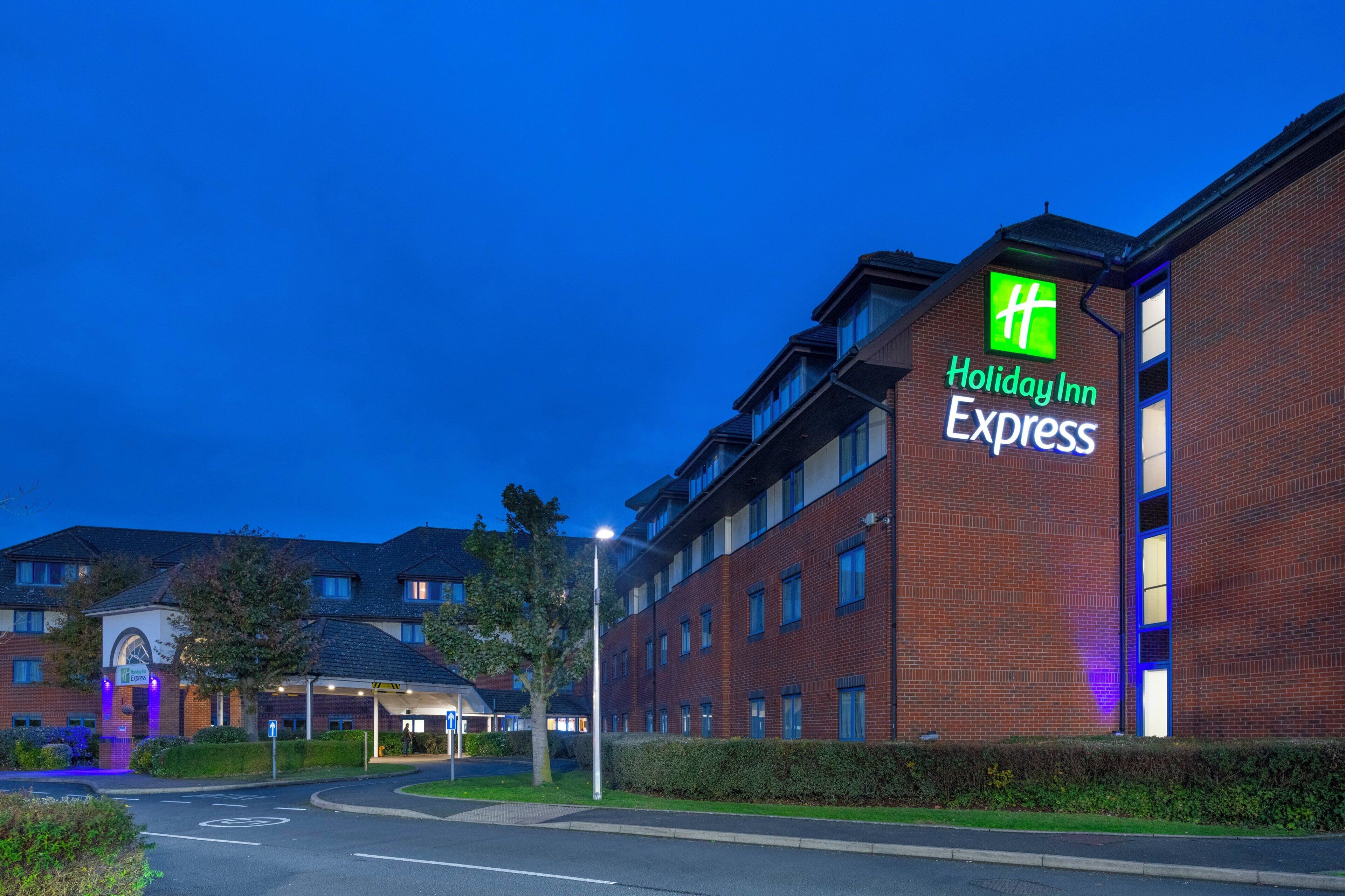 Edificio Holiday Inn Express con fachada de ladrillo, múltiples ventanas y una entrada bien iluminada.