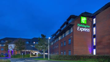 Edificio Holiday Inn Express con fachada de ladrillo, múltiples ventanas y una entrada bien iluminada.