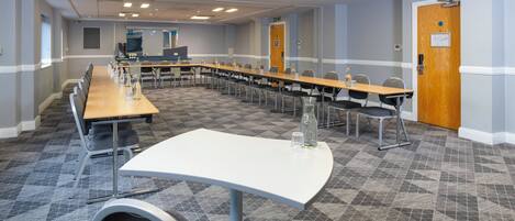 A conference room with a long table, chairs, and a whiteboard.
