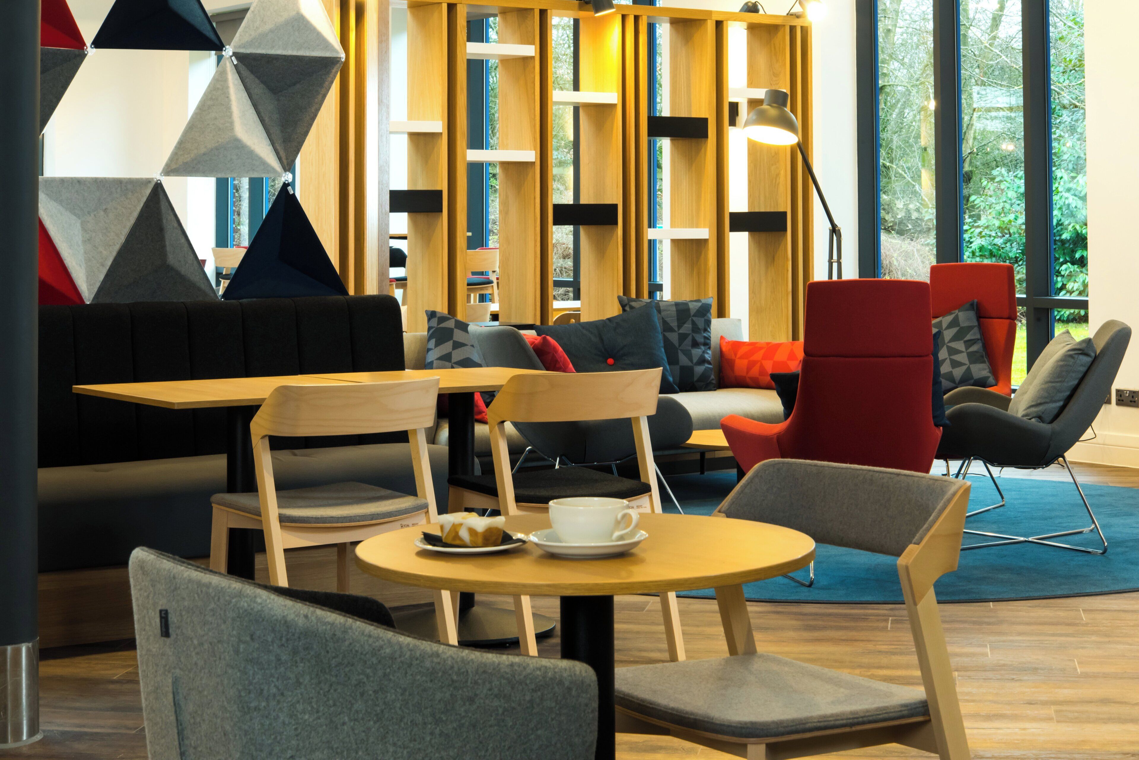 Ein stilvoller Lounge-Bereich mit Sitzgelegenheiten, Tischen und Blick auf Grünflächen.