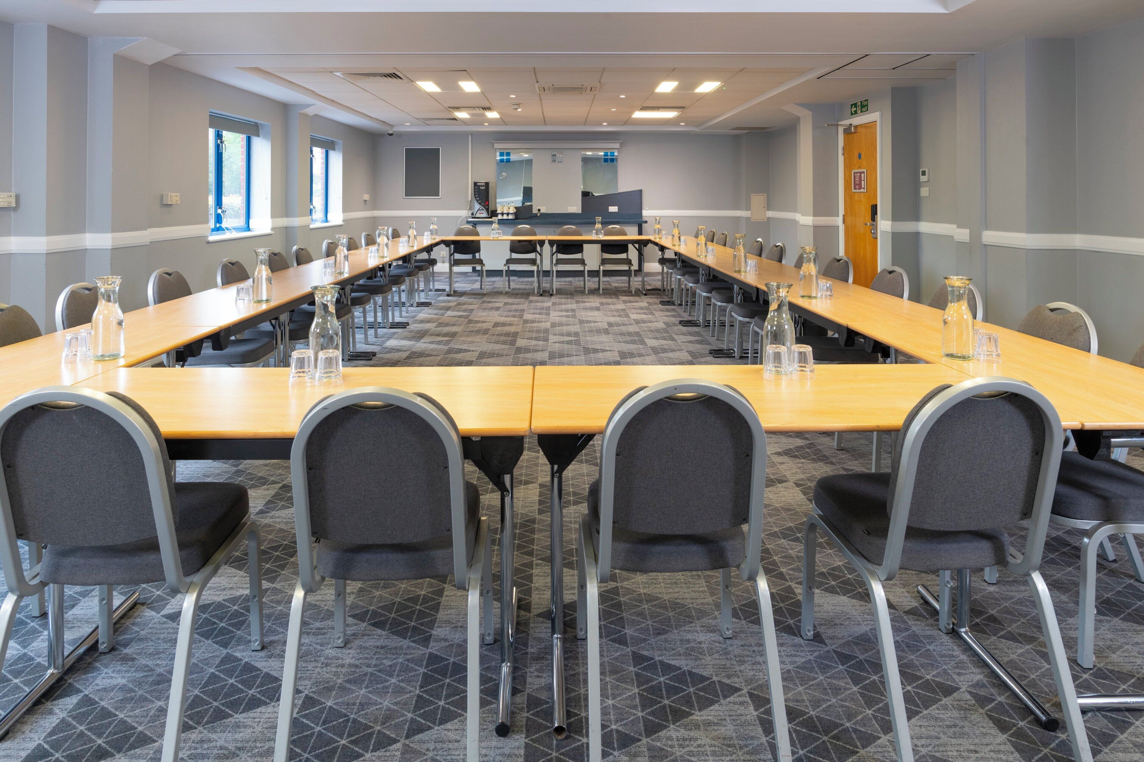 Une salle de conférence avec une longue table, des chaises et un pupitre.