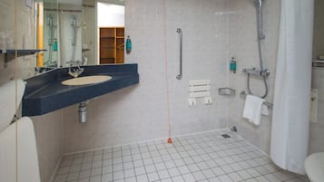 A modern bathroom with a sink, mirror, shower, and tiled floor.