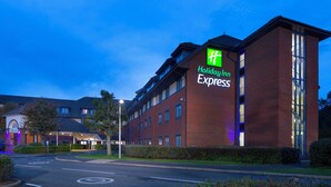 A Holiday Inn Express building with a prominent green sign, brick facade, and multiple windows. - Holiday Inn Express Birmingham Airport NEC by IHG (Birmingham)