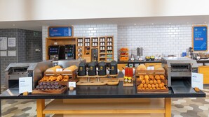 A breakfast buffet with various pastries, coffee machines, and a sign indicating 'Bring Home the Bacon'. - Holiday Inn Express Birmingham Airport NEC by IHG (Birmingham)