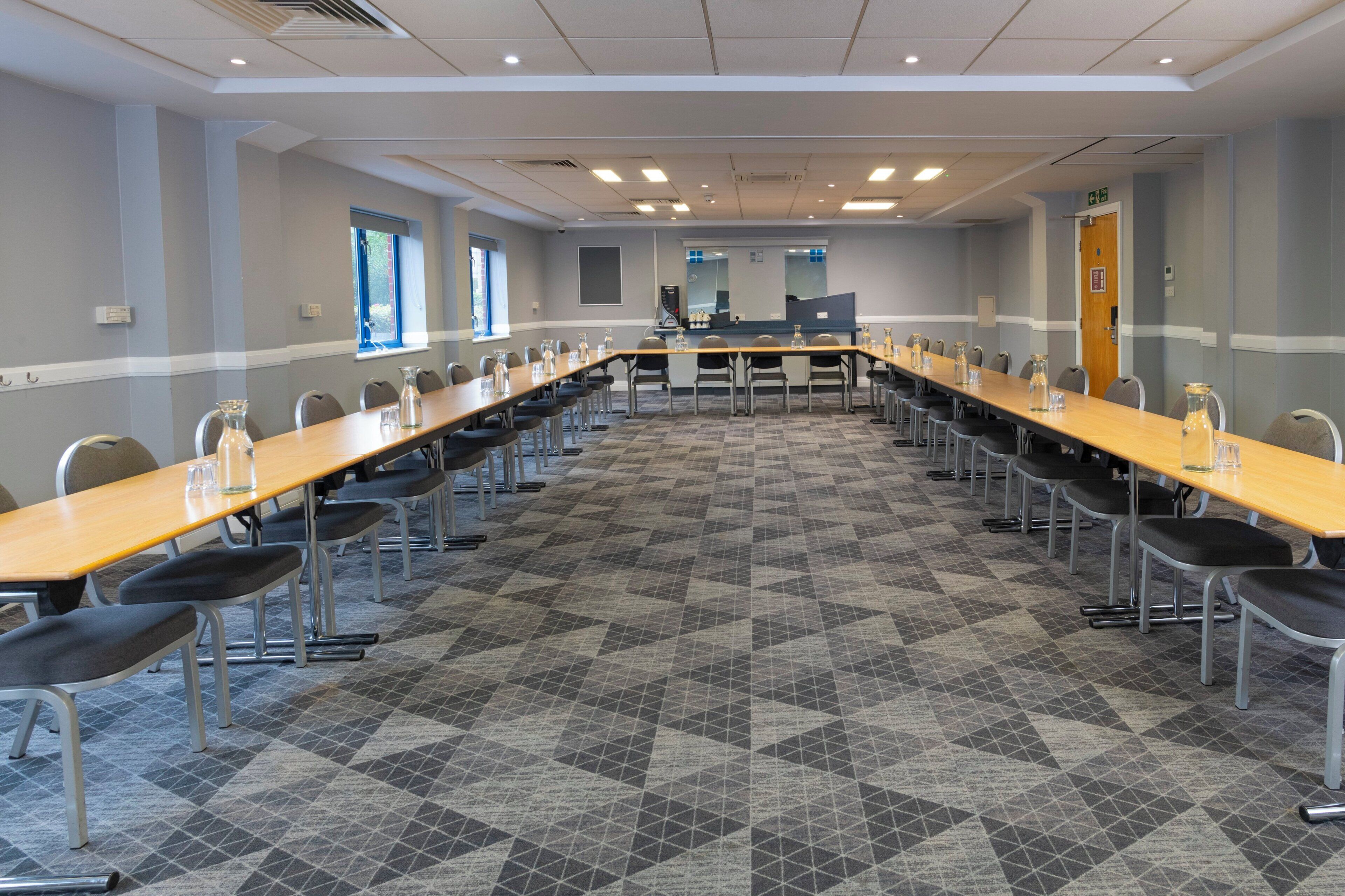 Una sala conferenze con un lungo tavolo, sedie e una tappezzeria decorata.