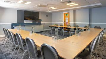A conference room with a long table, chairs, and a projector screen.