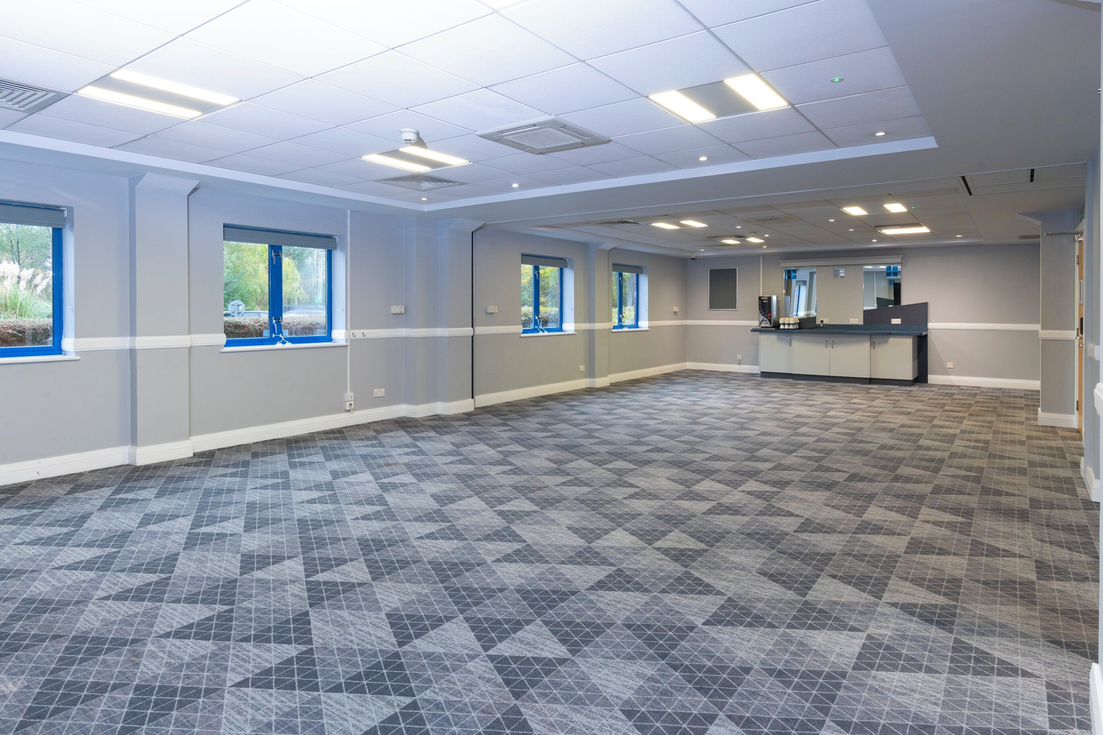 A spacious room with a check-in counter, large windows, and a patterned floor.