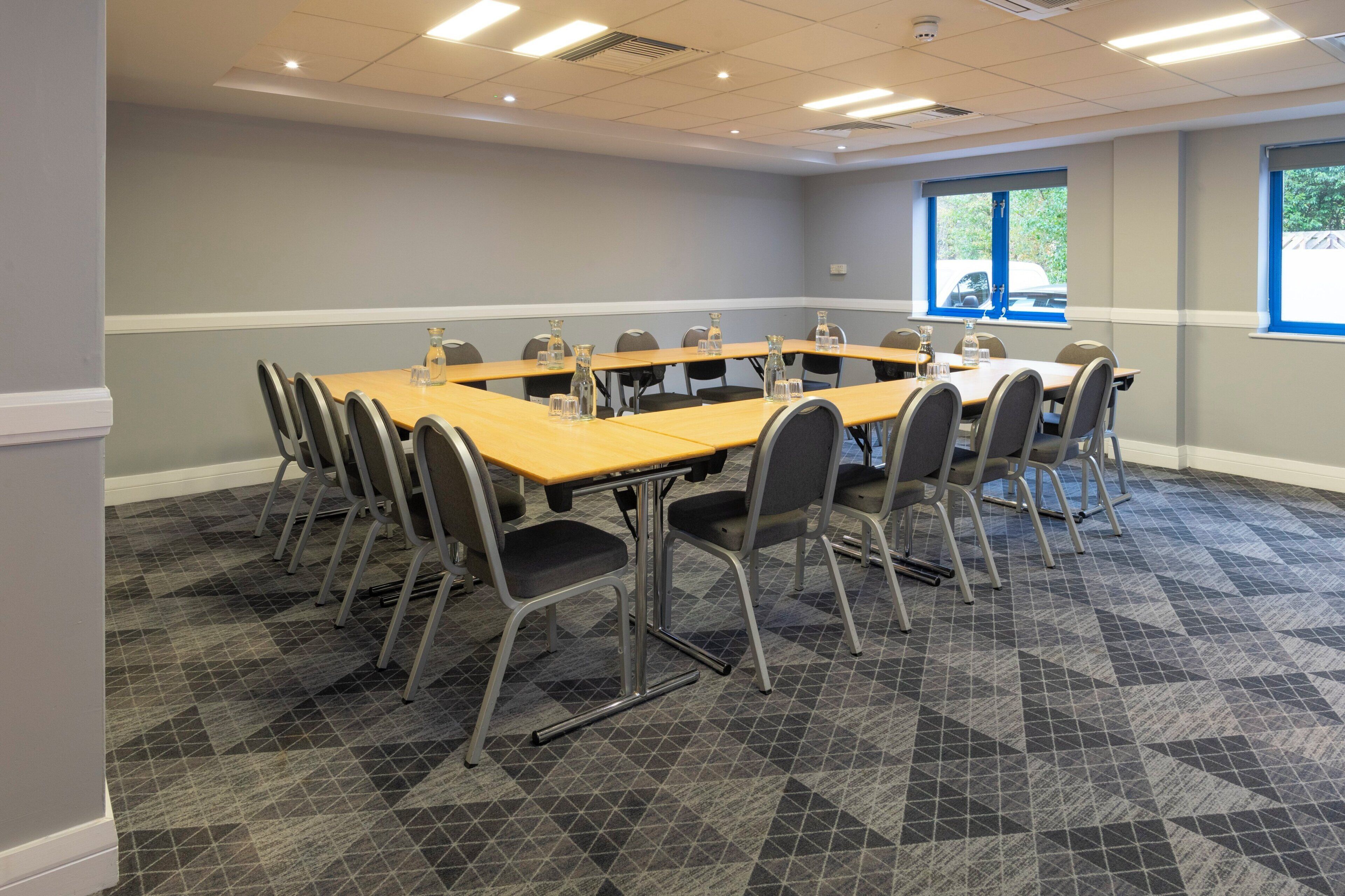A conference room with a long table, chairs, and a carpeted floor.