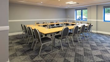 A conference room with a long table, chairs, and a carpeted floor.