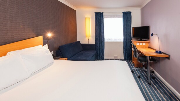 A hotel room with a large bed, a desk with a computer, a TV, and a lamp. - Holiday Inn Express Birmingham Airport NEC by IHG (Birmingham)