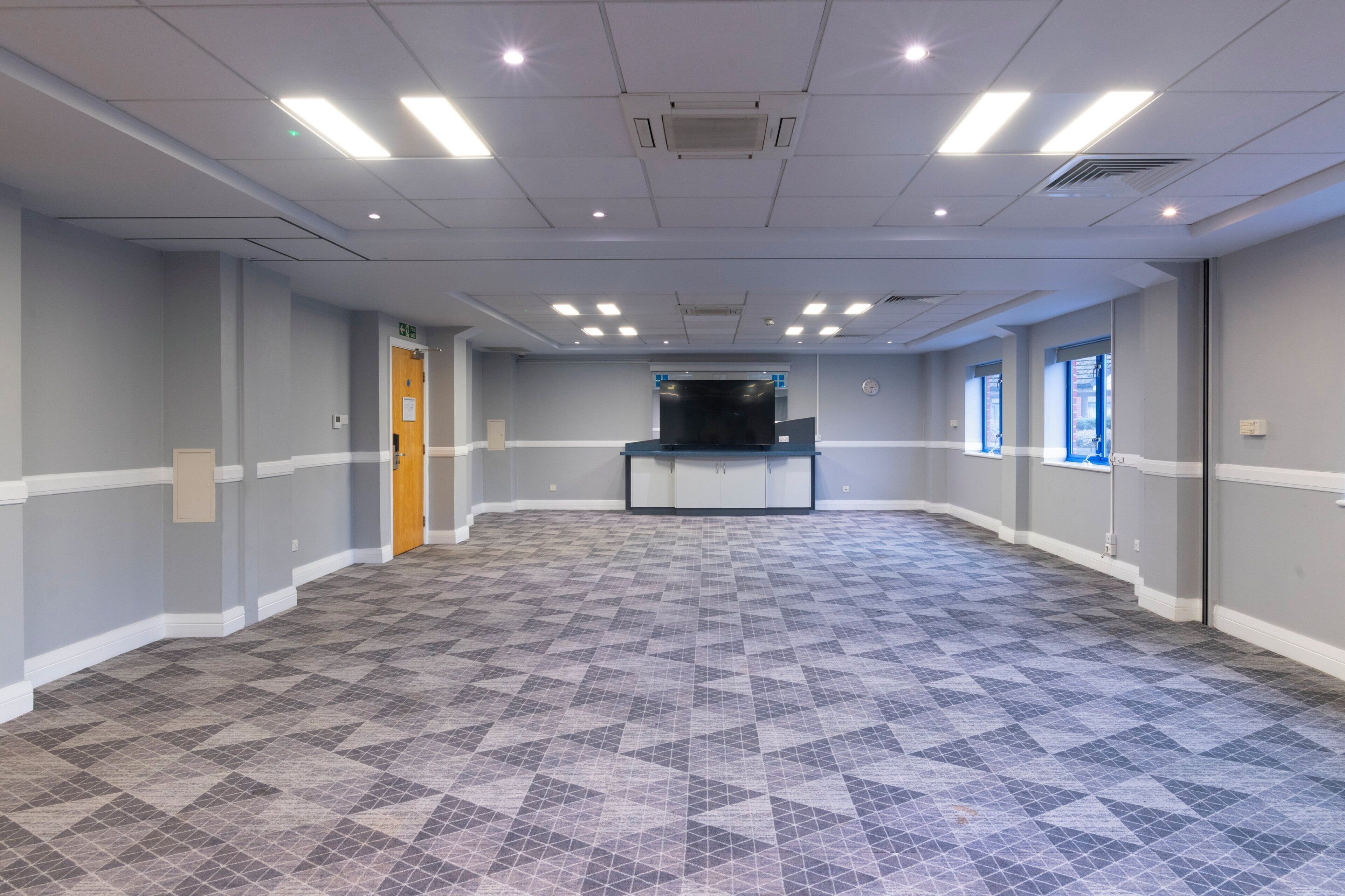 A spacious room with a patterned floor, a reception desk, and a door.