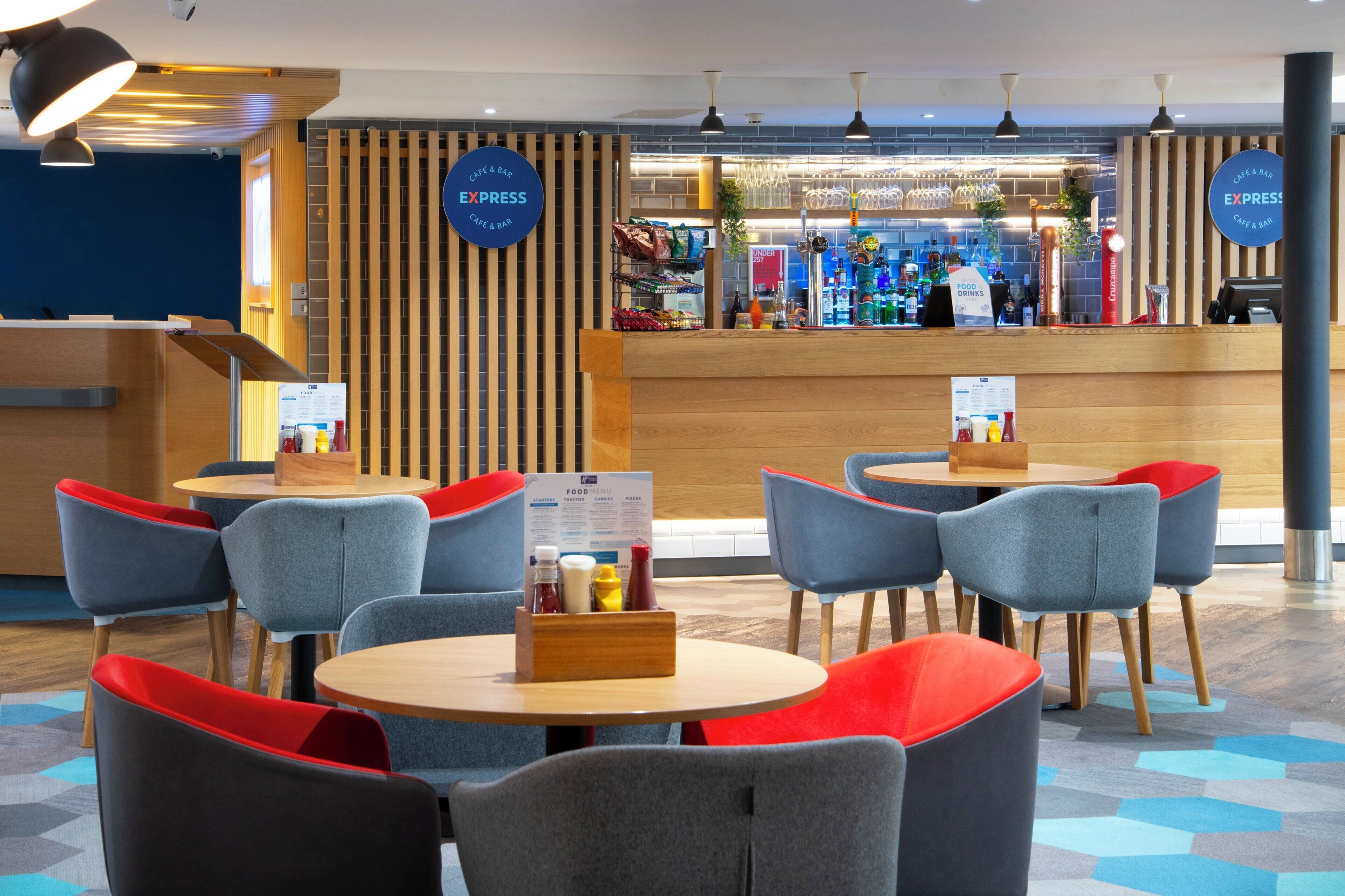 A cafe with round tables and chairs, a wooden counter, and menu boards.