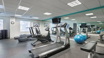 A gym with treadmills, exercise balls, and a mirrored wall.