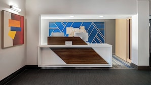 Un espace d’accueil au design moderne, comprenant un comptoir d’accueil, un mur bleu aux motifs géométriques et un tableau abstrait encadré.