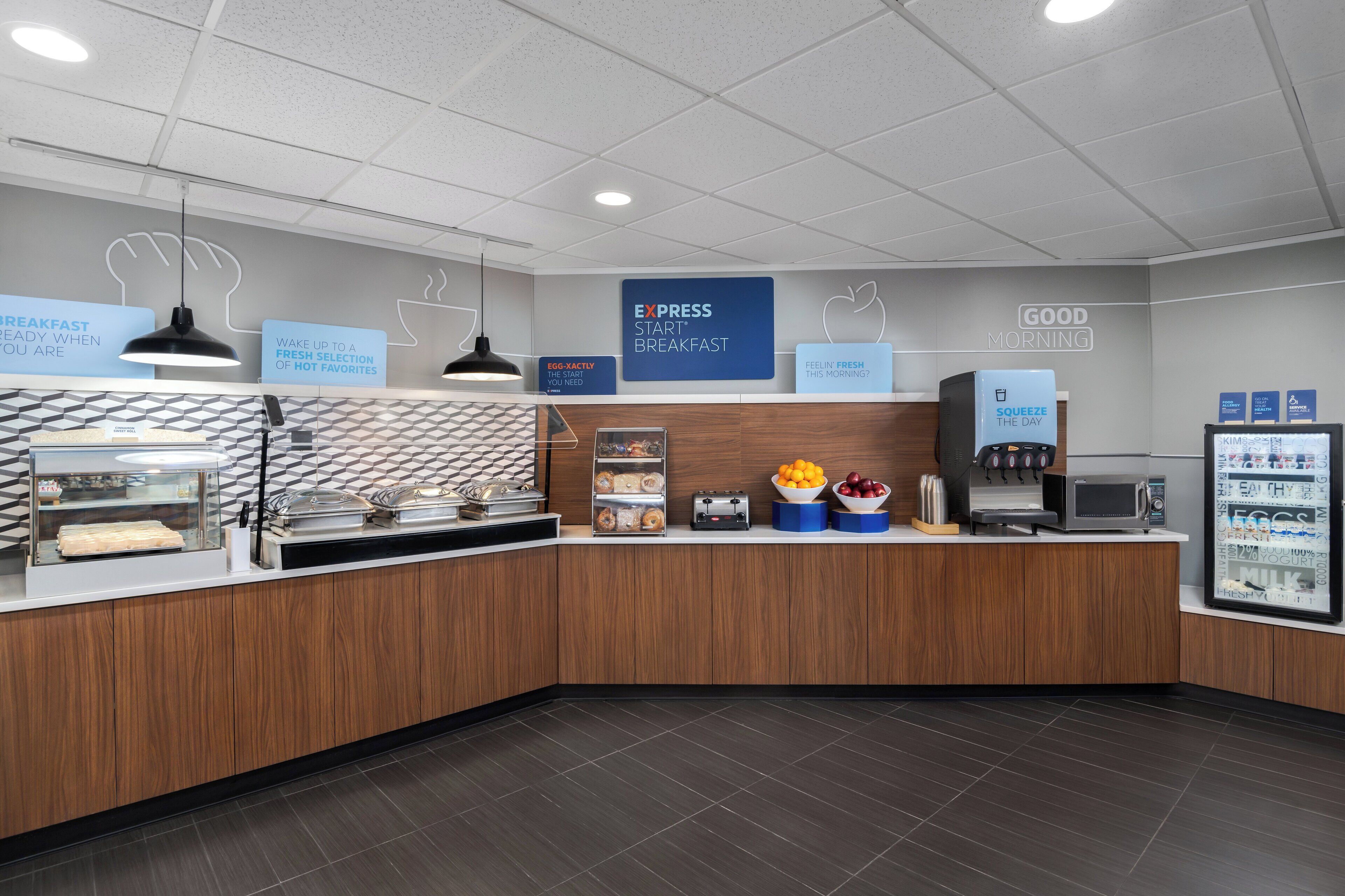 A modern breakfast area with a counter, a coffee machine, a microwave, and a refrigerator displaying food items.