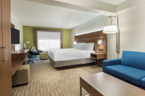 Une chambre d’hôtel équipée d’un lit, d’un bureau, d’une chaise, d’un canapé et d’une télévision.