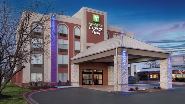 Un bâtiment de l’hôtel Holiday Inn Express & Suites, doté d’une façade moderne, de grandes portes d’entrée et d’un espace de stationnement couvert.