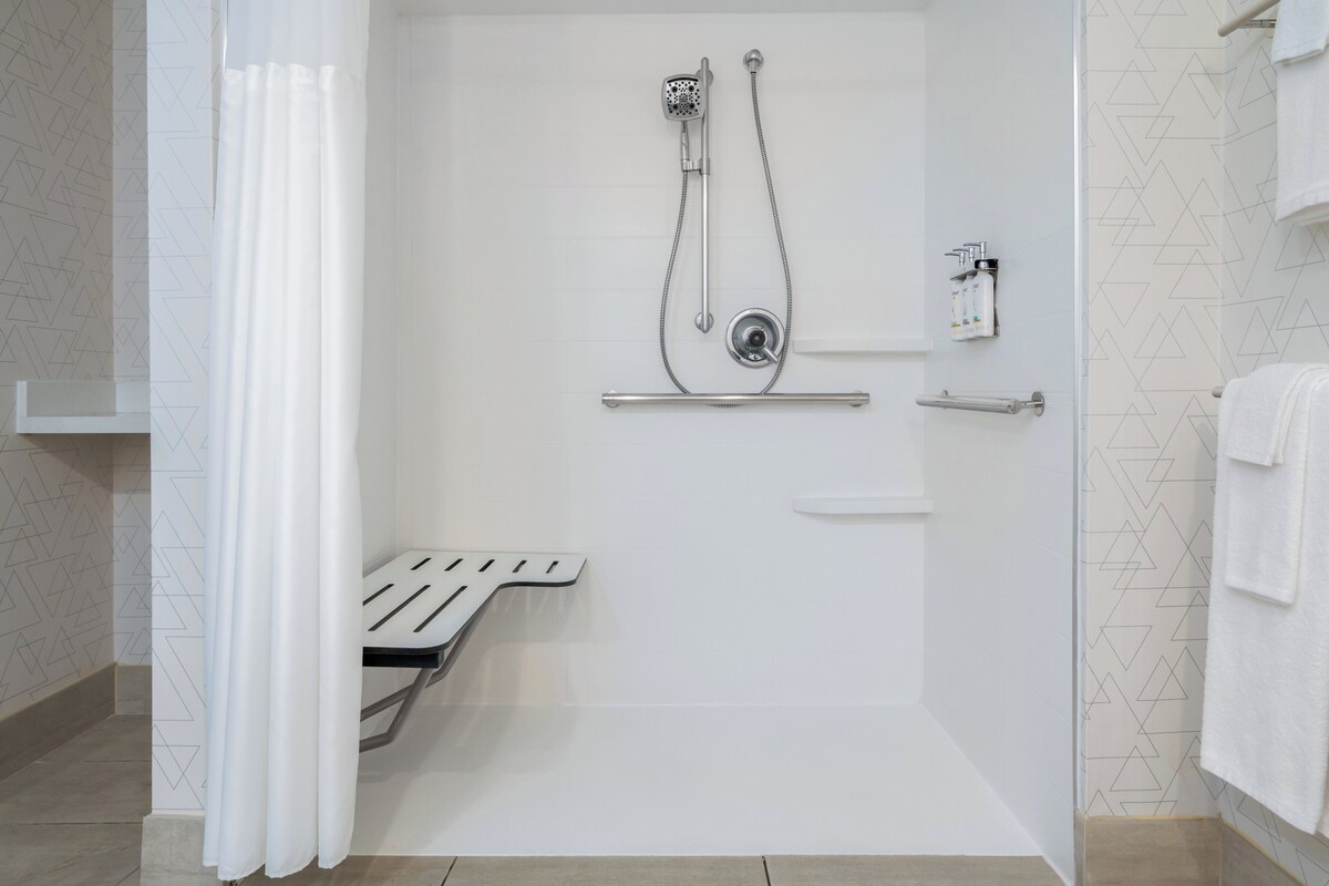 Un área de ducha moderna con cabezal de ducha de mano, llave de pared y toallero.