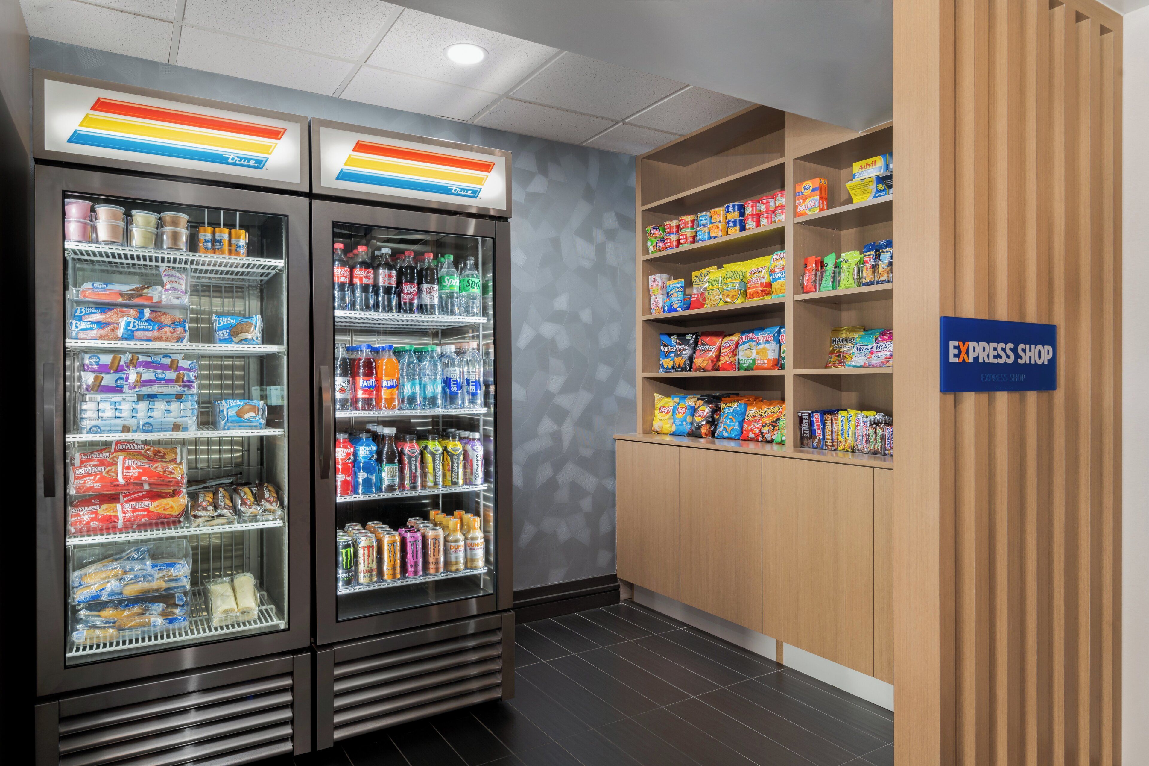 A self-service food area with refrigerated beverage dispensers and shelves stocked with snacks and beverages.