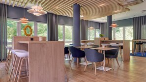 A modern interior with wooden flooring, bar seating, and large windows. - Holiday Inn Express Köln-Troisdorf by IHG (Troisdorf)