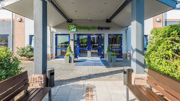 A Holiday Inn Express entrance with a blue and white facade, a covered walkway, and potted plants. - Holiday Inn Express Köln-Troisdorf by IHG (Troisdorf)