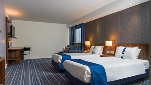 Ein Hotelzimmer mit zwei Betten, einem Schreibtisch und einem Stuhl.
