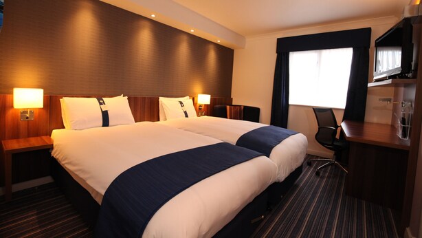 Ein Hotelzimmer mit zwei Betten, einem Schreibtisch und einem Stuhl.