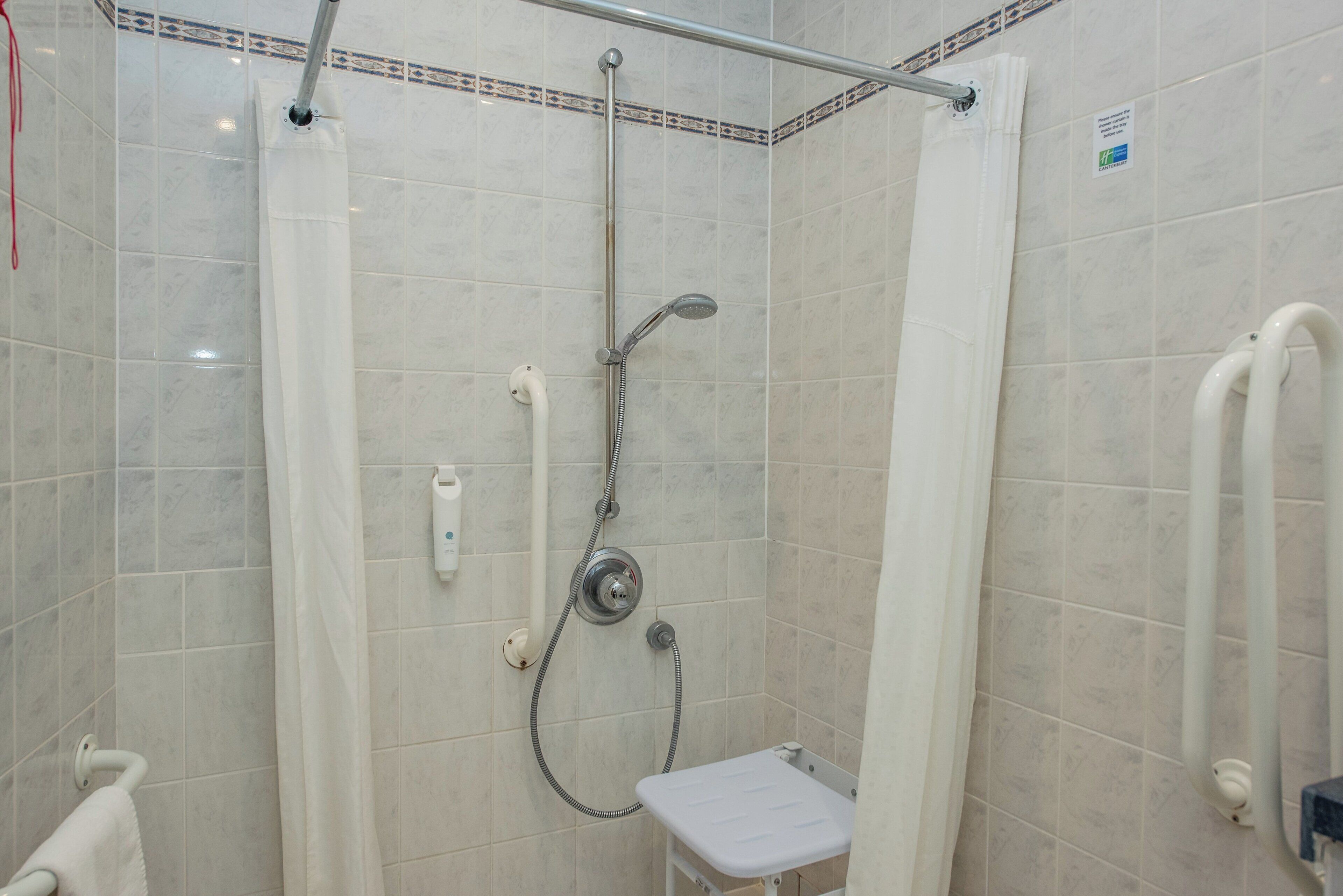 A shower area with a handheld showerhead, a handheld shower attachment, and a small white bench.