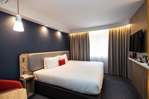 A hotel room with a bed, bedside table, lamp, TV, and curtains. - Holiday Inn Express Canterbury by IHG (Canterbury)