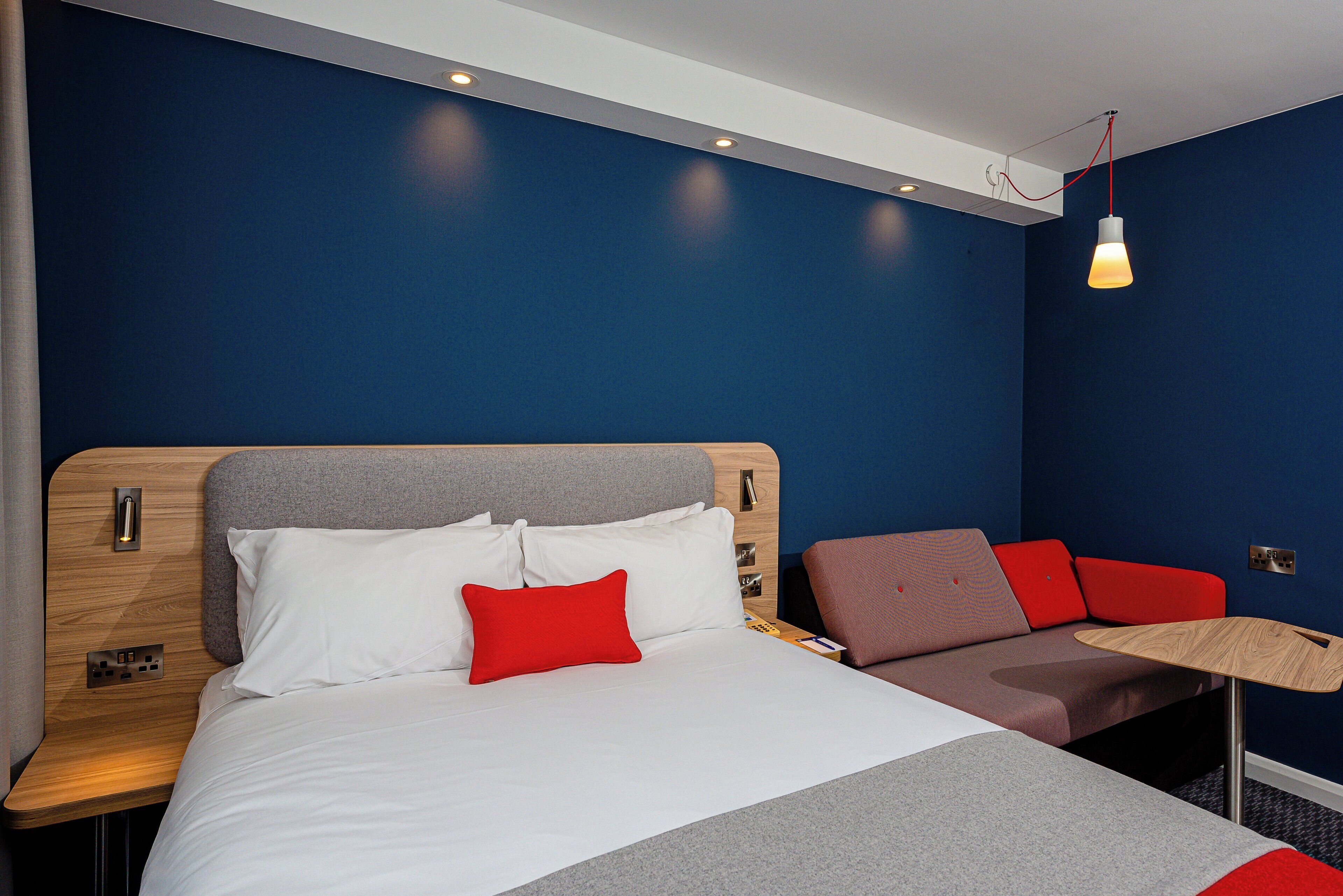 Una habitación de hotel moderna con una cama, una zona de estar y un escritorio.