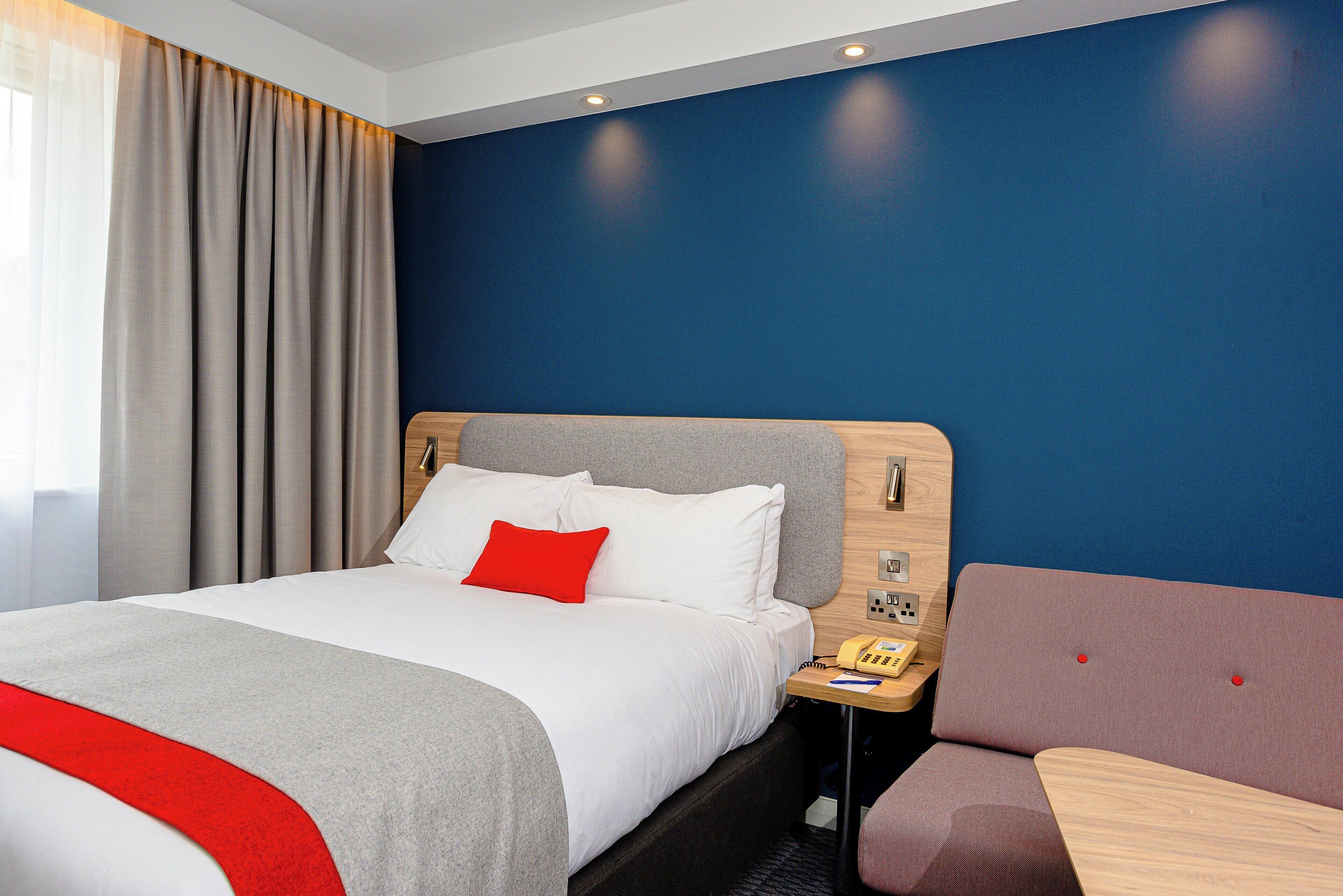 Ein Hotelzimmer mit einem Bett, einem Nachttisch mit Telefon und einer Sitzecke mit Tisch.
