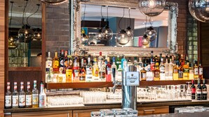 A bar area with a mirror, various liquor bottles, and glasses. - Premier Inn Essen City Limbecker Platz (Essen)