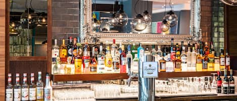 A bar area with a mirror, various liquor bottles, and glasses.