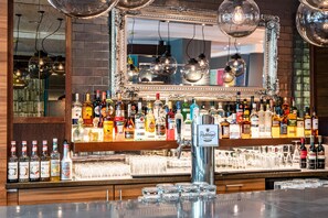 Un área de bar con un espejo, varias botellas de licor y vasos.
