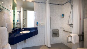 Une salle de bain équipée d’un lavabo, d’un miroir, d’une douche et de toilettes.