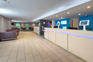 A hotel lobby with a reception desk, seating area, and a view of the outdoors. - Holiday Inn Express Exeter East by IHG (Exeter)