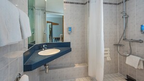 Une salle de bain équipée d’un lavabo, d’un miroir, d’une douche et d’une baignoire.