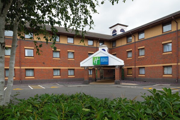Un bâtiment de la chaîne Holiday Inn Express, avec une façade en briques, de nombreuses fenêtres et une entrée abritée.