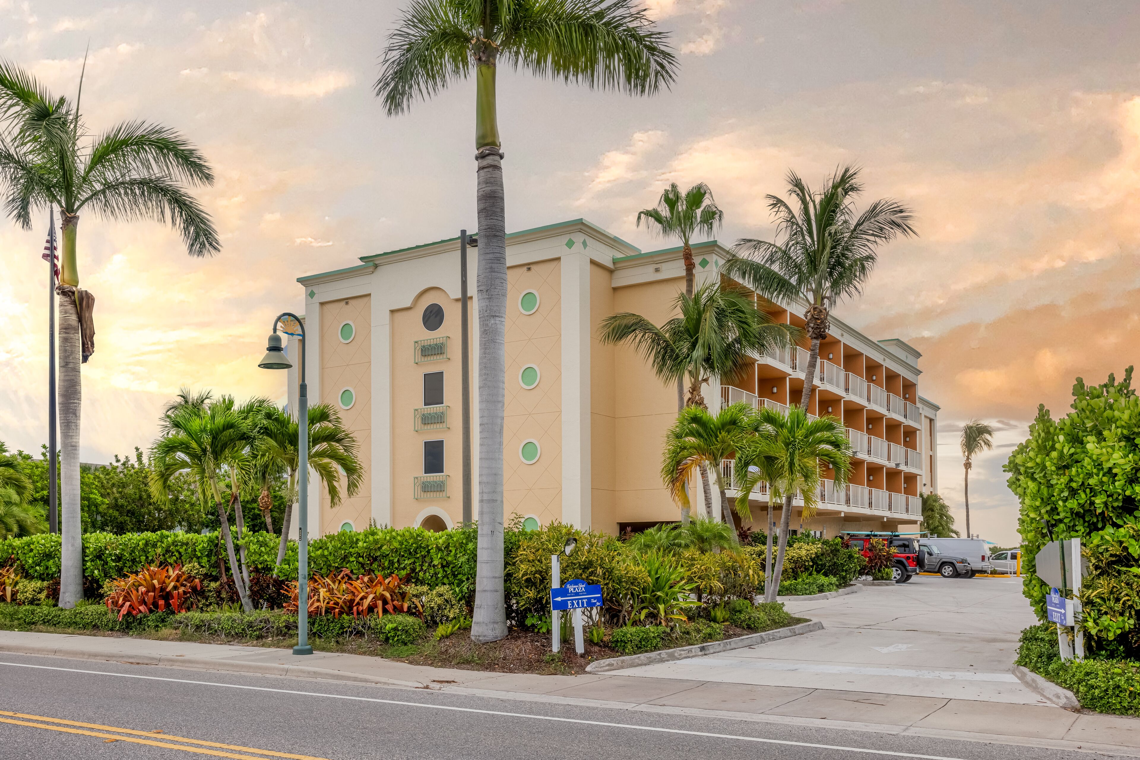 A hotel with a beige facade, multiple balconies, and palm trees.