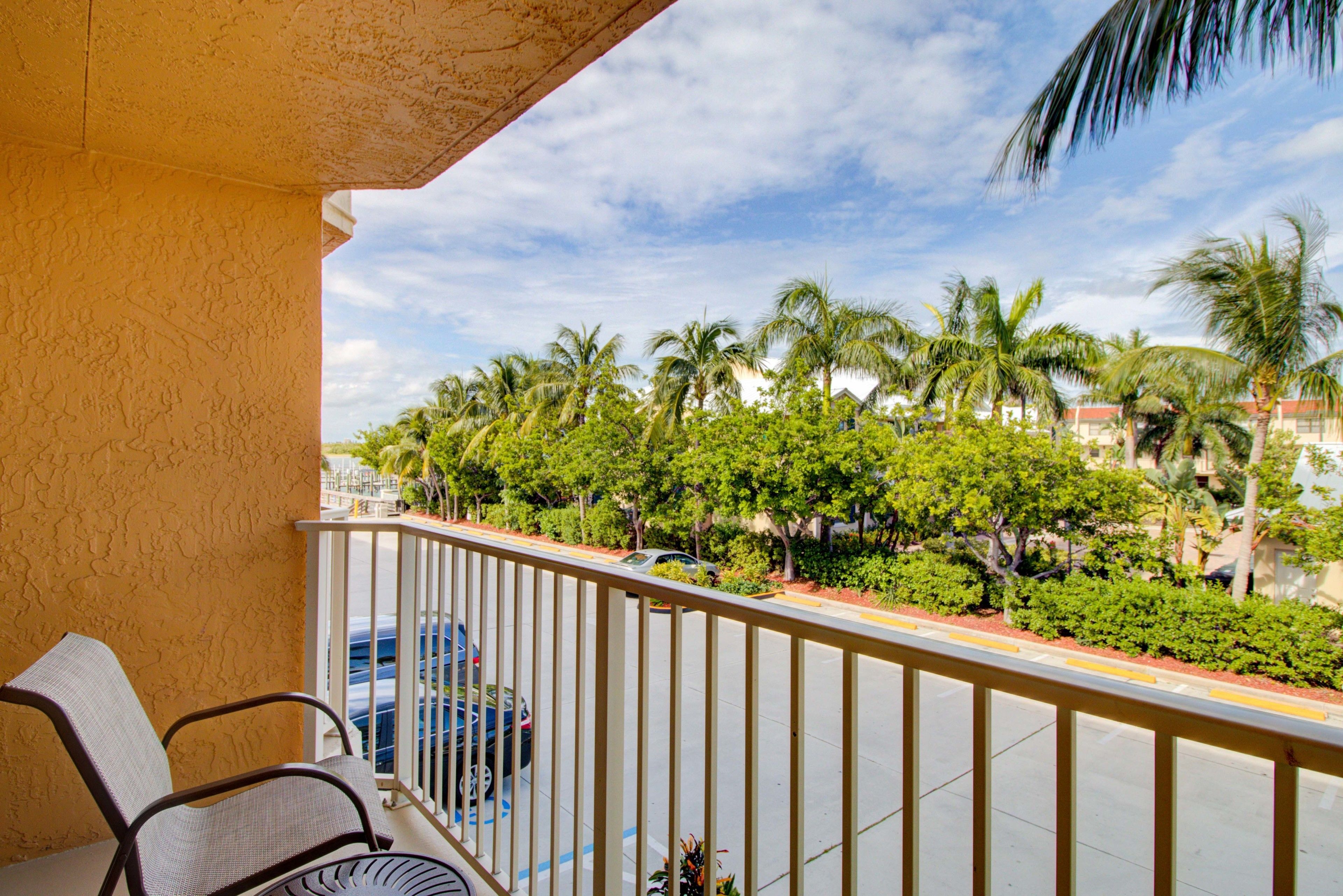 A balcony with a view of palm trees and a street.