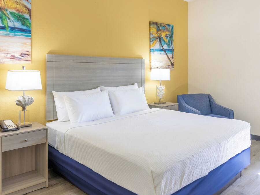 A hotel room with a bed, two bedside tables, a lamp, and a chair.
