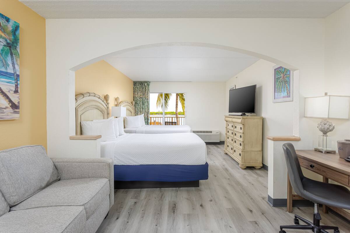 A hotel room with a bed, a desk, a TV, a dresser, and a couch.