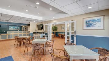 Un hall d’hôtel avec des meubles en osier, un coin cuisine et un tableau accroché au mur.