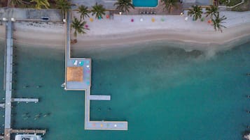 Ein Luftbild eines Strandes mit einem Steg, einem Schwimmbad und mehreren Booten.