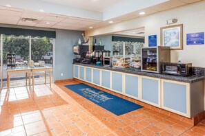 A hotel reception area with a counter, coffee machines, and a view of the outdoors. - Hutchinson Island Hotel (Fort Pierce)