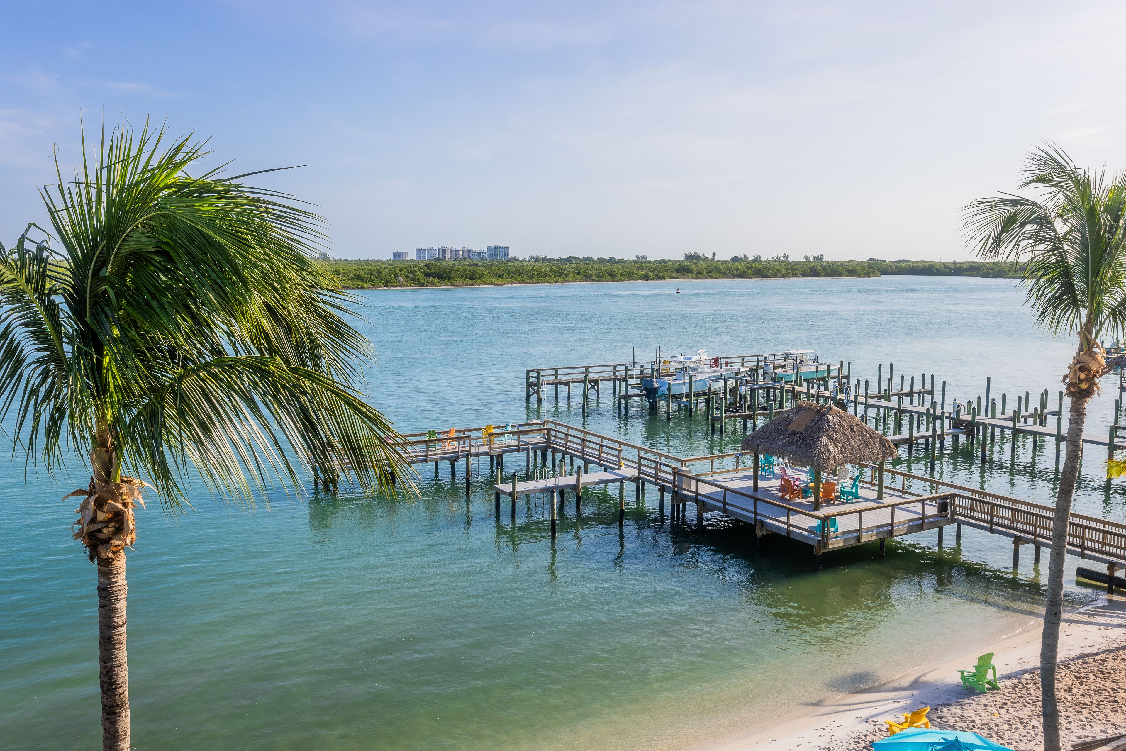 A pier with a thatched roof, wooden deck, and lounge chairs.