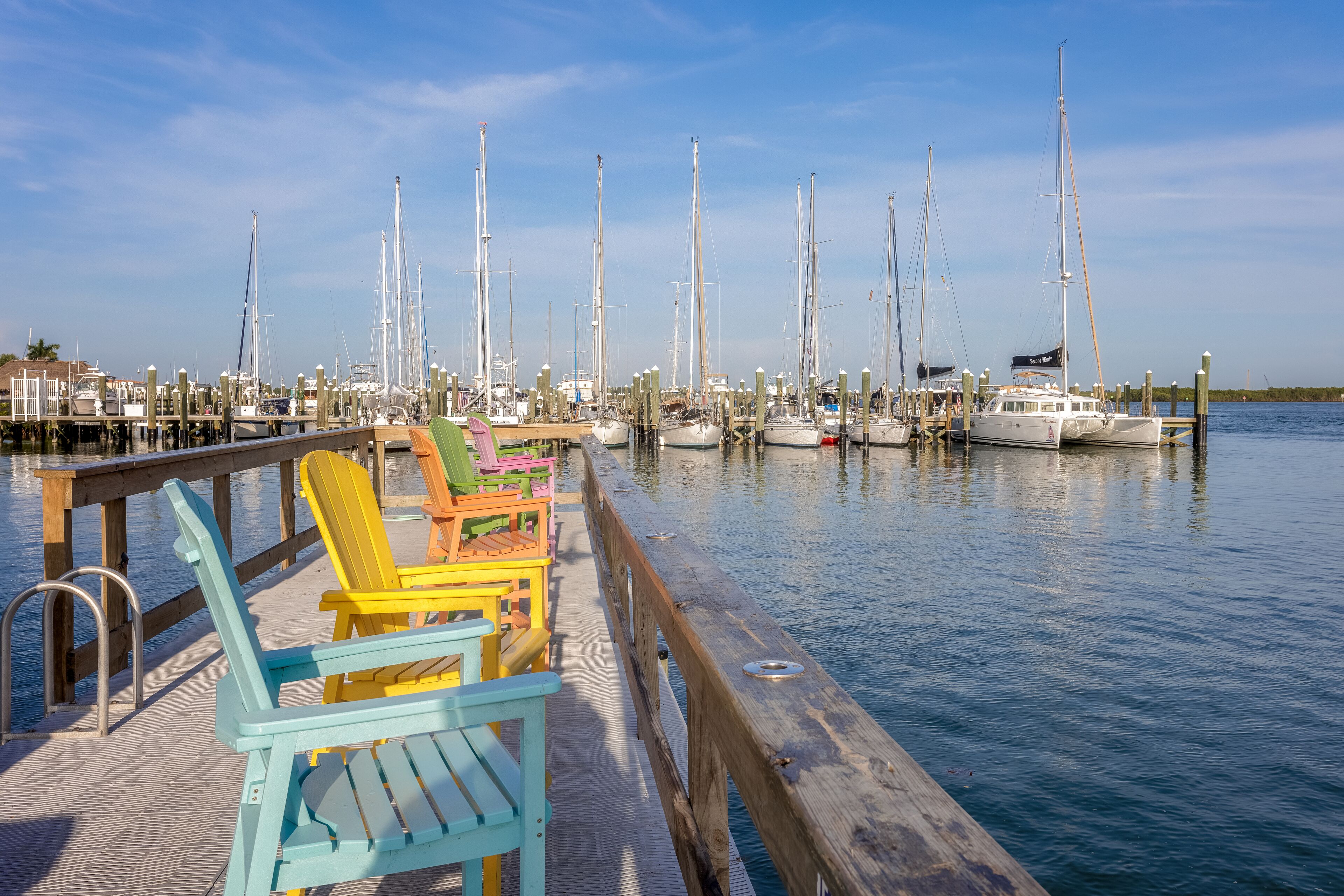 A marina with colorful Adirondack chairs on a wooden dock.