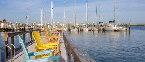 A marina with colorful Adirondack chairs on a wooden dock.