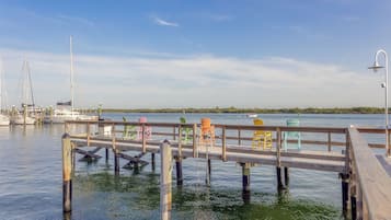 A wooden dock extending into calm waters with boats docked nearby and a clear sky above.