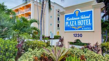 A sign for Hutchinson Island Plaza Hotel with a multi-story building and lush landscaping.